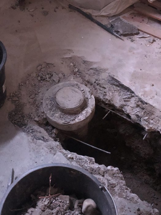 Gammal betong rensbrunn i grävd grop med jämnt betonggolv runtom, redo för rörbyte.
