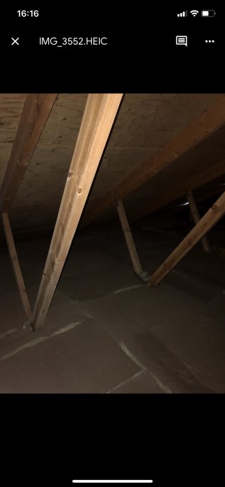 Takstolar i trä synliga i ett mörkt utrymme som skall öppnas upp för att avtäcka nocken.