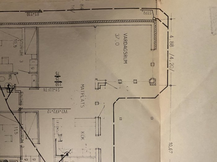 Arkitektonisk skiss av husplan med mått för vardagsrum och angränsande utrymmen.