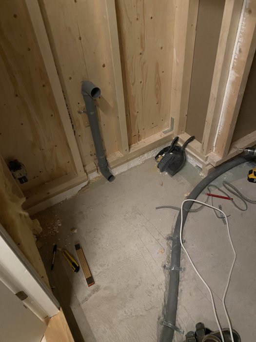 Nyinstallerat avloppsrör och uppbilad fåra i betonggolvet vid en renovering.