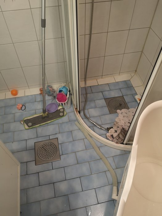 Helkaklat badrum med duschhörna och golvbrunn, föremål på golvet, avser renovering och utökning.