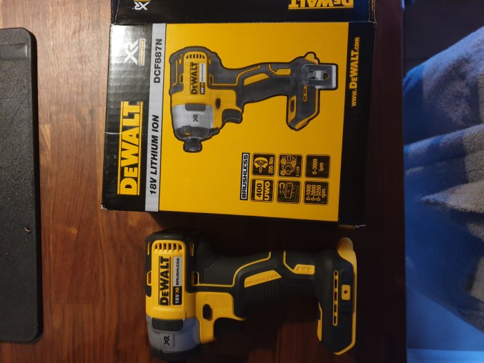 Ny Dewalt DCF887 slagskruvdragare bredvid sin förpackning på ett bord.