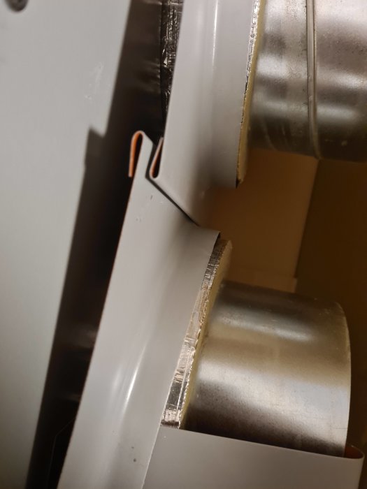 Överlappande vita plåtpaneler med en metallrörskant som ser fel ut.