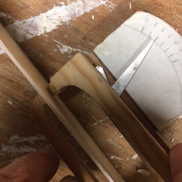 Close-up av en handgjord tjockleksmätare som mäter tjockleken på 2 mm tunna lönnträskivor för fiolbygge.