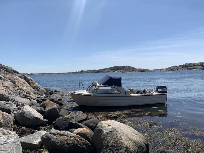 Askeladden 16-4400 båt från 1985 med 40 hk motor förtöjd vid klippig strand på en solig dag.