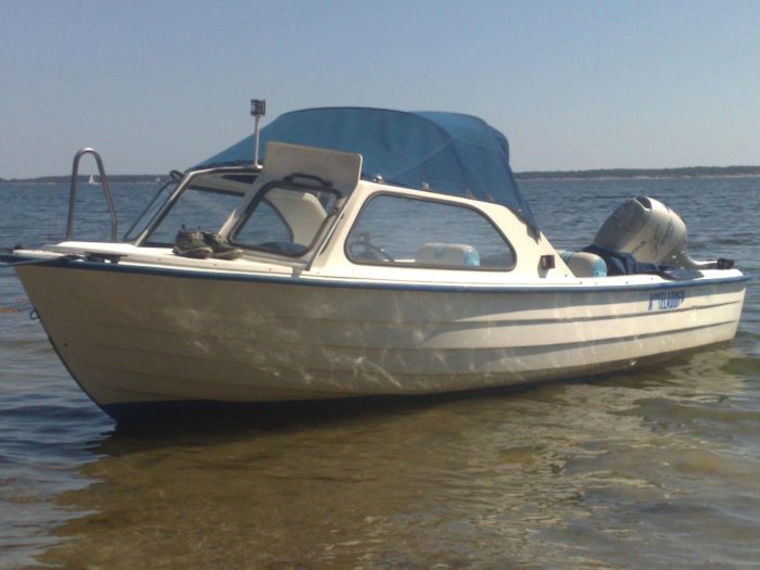 Askeladden 635 WA motorbåt förtöjd vid en strand med skyddande kapell och utombordare.