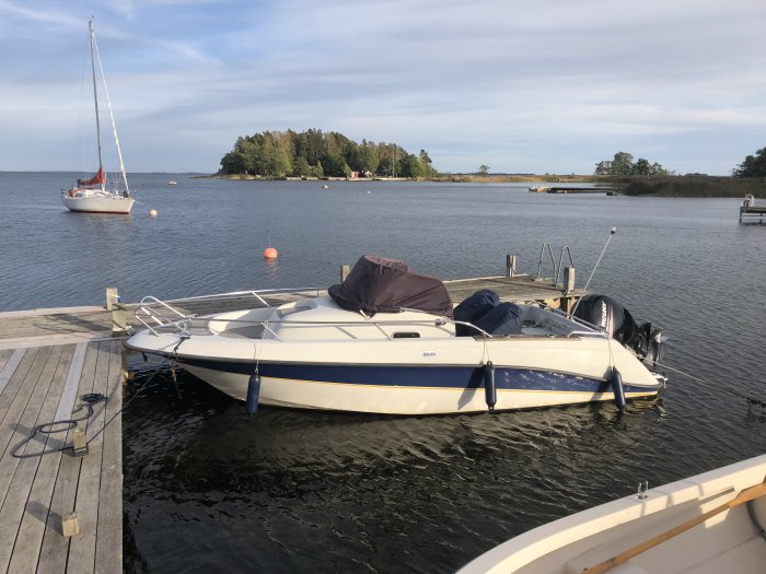 En Askeladden 635 WA motorbåt förtöjd vid en brygga med segelbåt i bakgrunden.