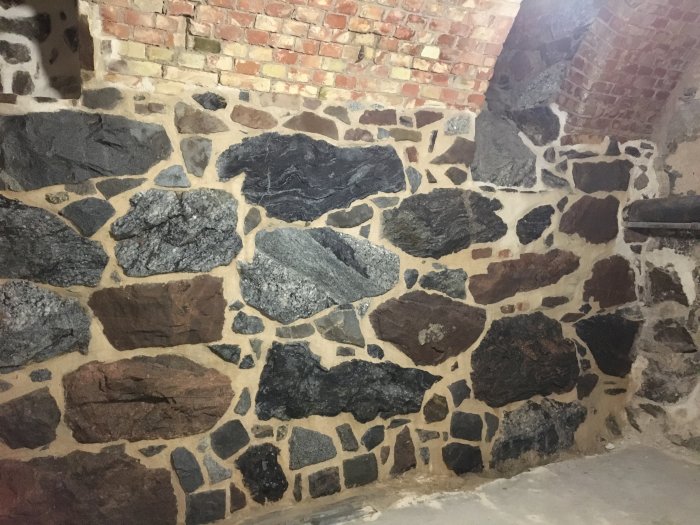 Nyrenoverade väggar med oregelbundna stenar och mursbruksfogar i ett inomhusrum.