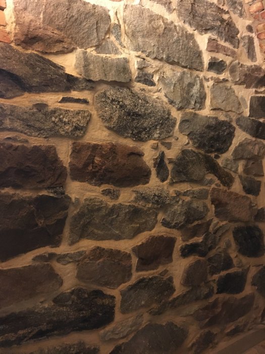 Nyligen färdigställda väggar med oregelbundna stenblock i olika nyanser och storlekar.
