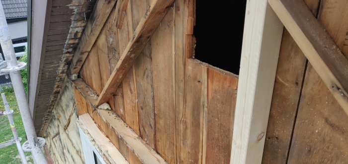 Bild på en avtäckt yttervägg på ett hus med synliga träribbor och isolering vid renovering.