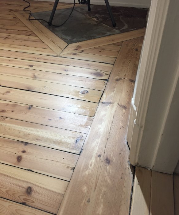 Nyslipat trägolv med ojämn betsning och hårdvaxoljebehandling vid en dörröppning.