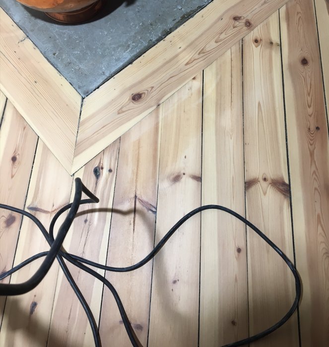 Nyslipat trägolv med ojämn betsning och hårdvaxoljebehandling nära en betongkant.
