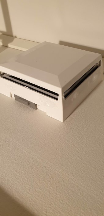 Vit ventilationsanordning på vägg med kondens runtomkring som droppar ner.