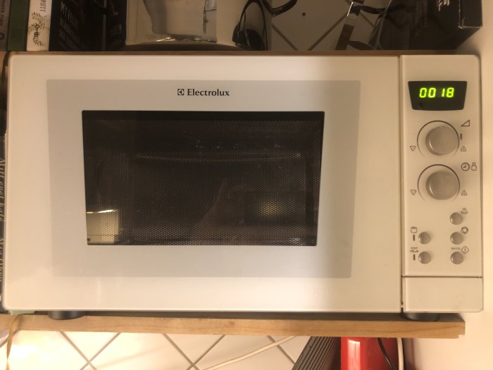 Electrolux mikrovågsugn som visar tiden 00:18 på displayen, lampan tänd inuti med stängd lucka.