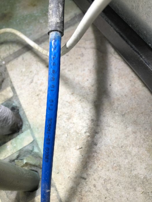Närbild av en värmekabel med beteckningen skrivet på en blå isolering.