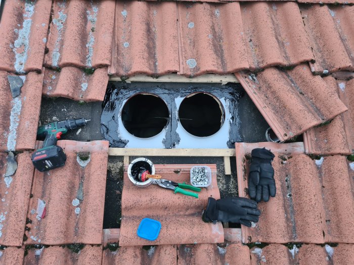 Tak med installerade ventilationstrummor, verktyg och byggmaterial syns.