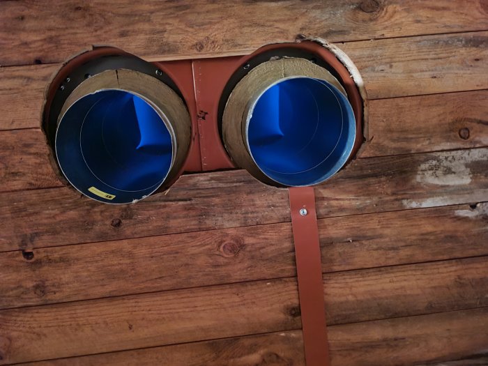 Ventilationsrör installerade i en trävägg, med inre blå beläggning synlig.