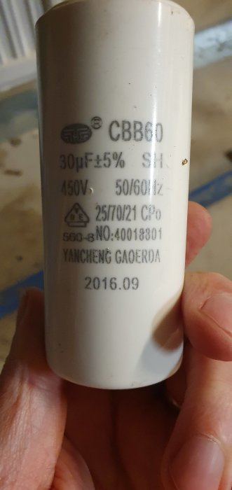Hand håller en kondensator med tekniska specifikationer, misstänkt defekt med 0 Ohm mätvärde.