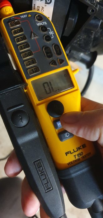 Multimeter med displayen som visar 0 Ohm i en hand, möjligen kondensatortest.