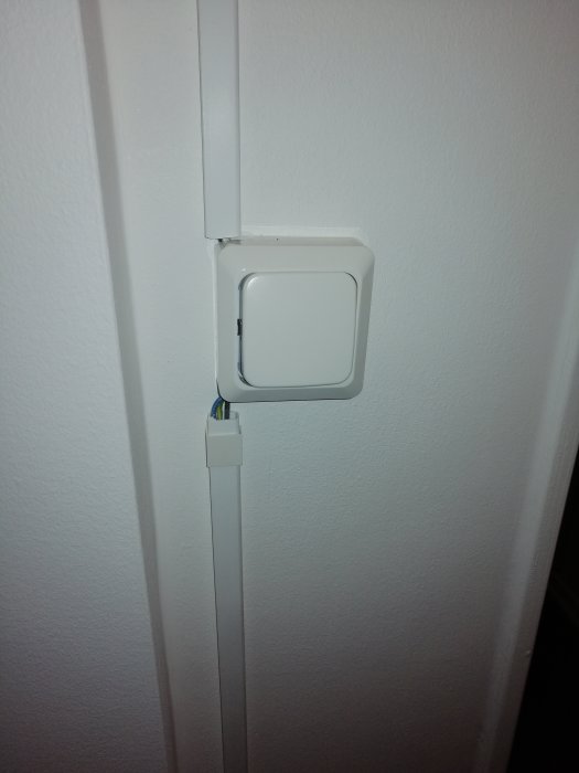 Strömbrytare med oskyddad, synlig kabel och kabelkanal på en vägg, ger intryck av osäker installation.