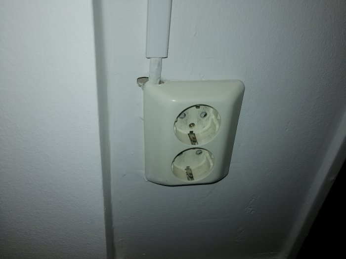 Vägguttag med synlig kabelkanal och slarvigt installerad el i en bostad.