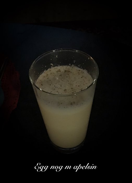 Egg nog med apelsin och mörk rom i ett glas, toppat med kryddor.