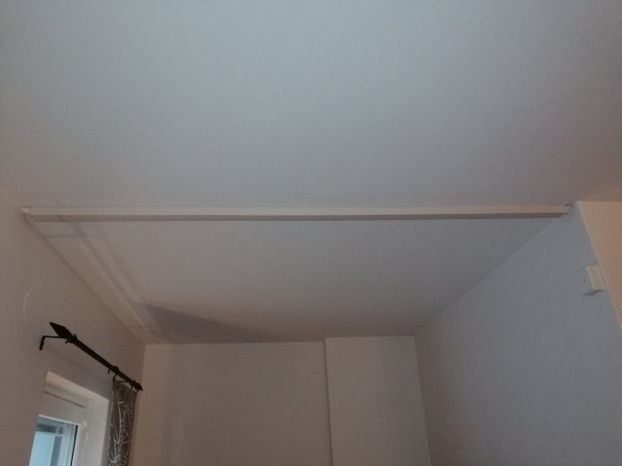 Kabelkanal som löper över ett rumstak och avslöjas där puts eller spackel har tagits bort.
