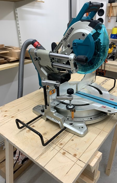 Makita LS1019L gersåg på arbetsbänk med ansluten dammsugar slang och hållare.