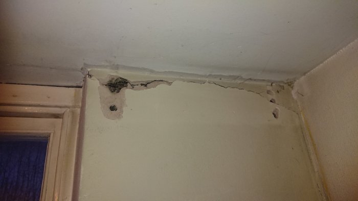 Rivna murputs och stora sprickor i övre delen av en källarväggs hörn nära taket.