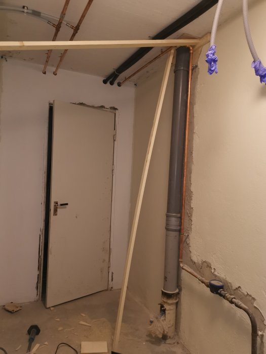 Avloppsrör installerade i ett badrum under renovering med synligt gjutet hål i valvet och verktyg på golvet.