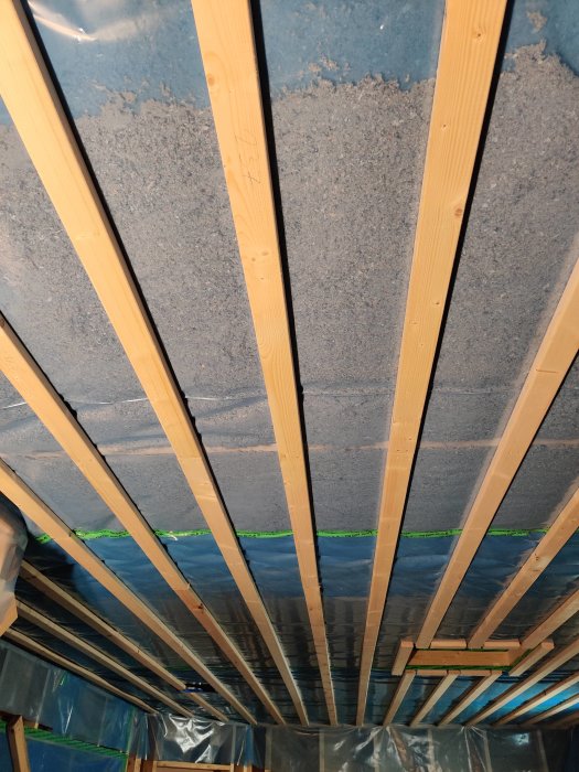 Nyisolering av tak med synliga träbjälkar och isoleringsmaterial.