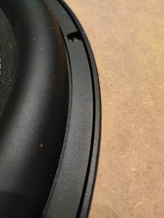 Närbild på ett bas-element provmonterat i en uthuggen MDF-bräda för en hemmabio baslåda.