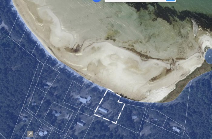 Satellitbild av strandnära område med markerade fastighetsgränser och byggnader.