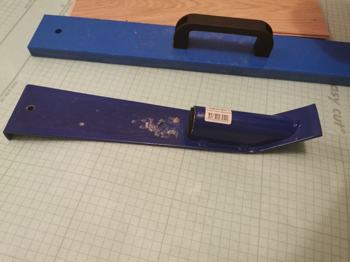 En blå slagkloss från Tarkett och ett avskalat verktyg på ett rutigt underlag.