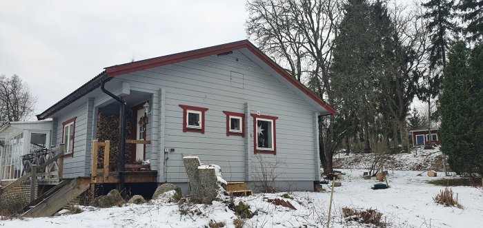 Hus med borttagna altandelar och upplockad marksten i en trädgård med snö.