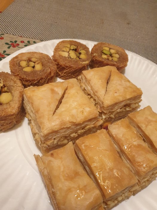 Olika sorters baklava med nötter på ett vitt fat.