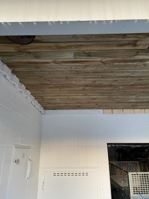 Bild på undertaket av en balkong med synliga träplankor och bultar där de är fästa i husets vägg.