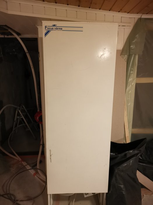 Varmvattenberedare märkt "Focus värme" står temporärt placerad i ett under-renoveringsutrymme.