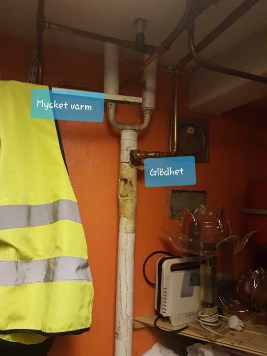 Rörsystem med temperaturmärkningar i ett pannrum, synlig varseljacka och diverse föremål.