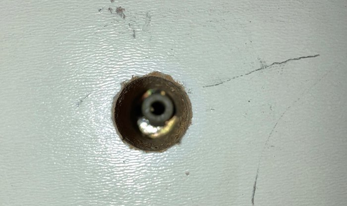 Närbild på ett 10 mm hål i vindslucka med synlig mekanism som liknar en fjäder inuti.
