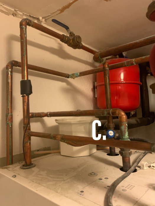 VVS-installation med kopparrör, expansionskärl och tryckmätare markerad med (B.) samt ventilen (C.)