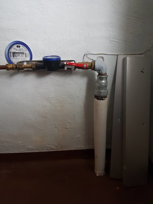 Vattenmätare och ett gammalt galvaniserat stålrör i ett hus.