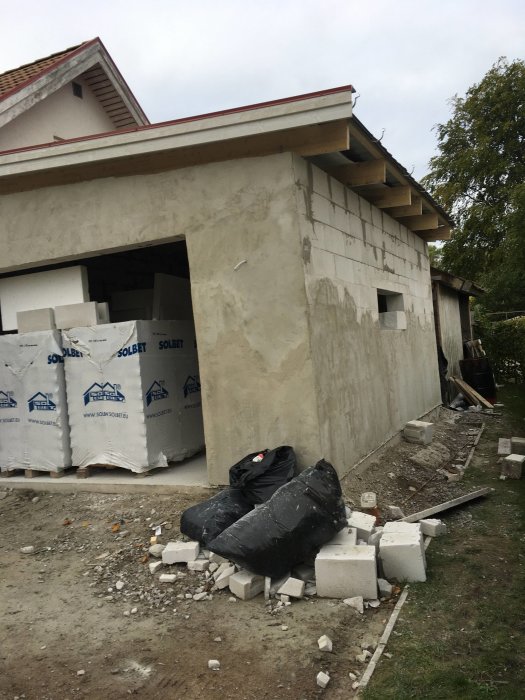 Ett nästan färdigt garage byggt av Siporex-block och putsad yta med byggmaterial och skräp framför.