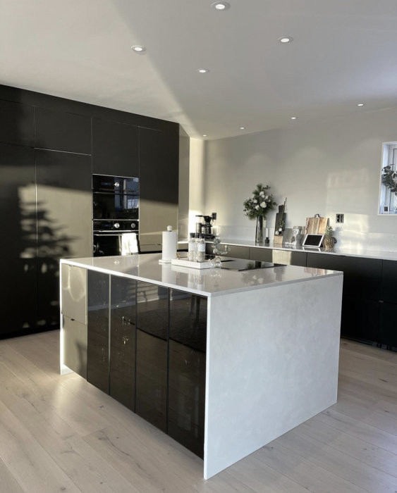 Modernt kök med svart inredning och köksö utan socklar monterade.