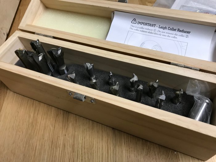 Öppen träask med ordnat set av metallstålförvaring för Leigh D4R Pro DoveTail Router Jig, inklusive tillbehör och manual.