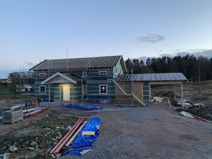 Hus under renovering med ny spikläkt och carportpelare synliga, samt tillagda fönster i vägglivet.