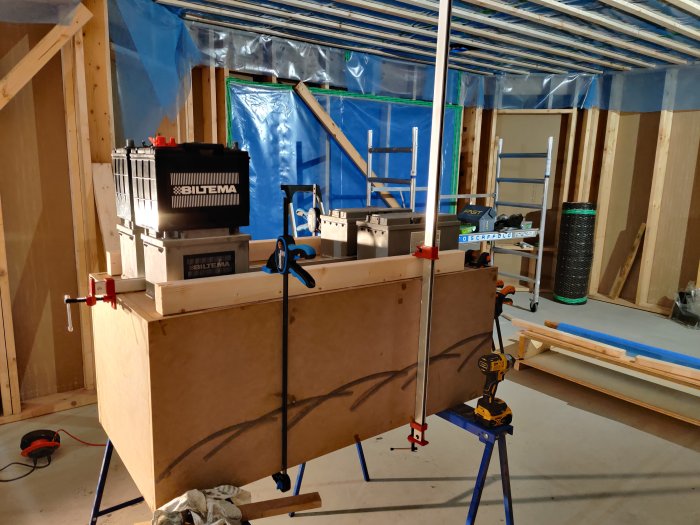 Bild på en oisolerad byggnadsställning med verktyg och en baslåda under konstruktion i ett pågående byggprojekt.