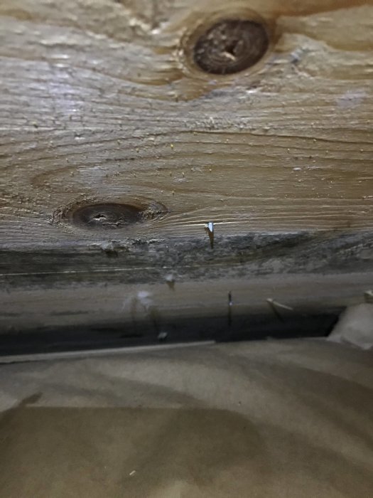 Insida av yttertak med tecken på mögel och dålig ventilation, synlig isolering i förgrunden