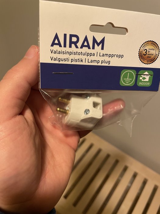 Hand håller en förpackad jordad lamppropp märkt AIRAM, avsedd för inomhusbruk.