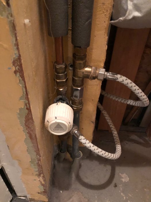 Värmesystem med T-kopplingar och termostat, gråa slangar till golvvärme som är kalla i badrum.